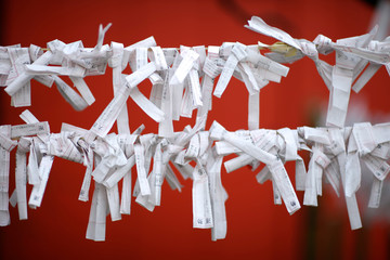 White strips of paper with prayers and wishes of believers on the ropes near the walls of a Buddhist temple