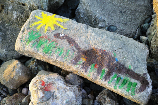 The dinosaur and the sun painted on the stone.