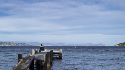 Sad hipster woman sitting on the pier with sadness.