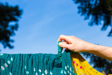 eine Frau hängt frisch gewaschene Wäsche auf eine Leine
