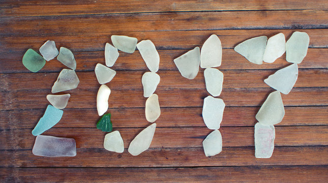 Beach glass decor on wooden background. 2017 New Year sea glass mosaic. - Powered by Adobe