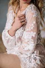 Bride's morning. Fine art wedding. Portrait of a young bride in white lace boudoir with wavy blonde hair and a bouquet