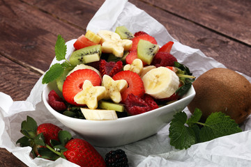 Bowl of healthy fresh fruit salad on wooden background