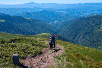Travelers man and boy with backpacks descend along the ridge