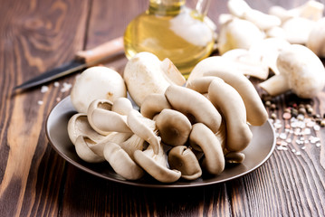 Fresh mushrooms on a wooden background  Bottle with olive oil