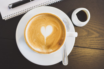 Cup of coffee , note and pen on wood table.