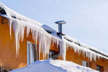 In the winter icicles are hanging on a building roof