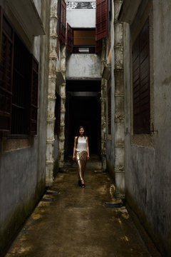 Young woman walking down narrow alley between buildings