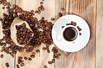 cup of coffee with grains on the wooden background