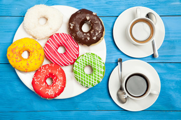 Two cups with coffee and donuts on a blue wooden table