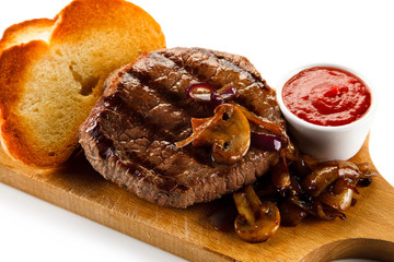 Grilled steak and toasts on wooden board