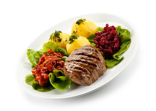 Grilled steaks, boiled potatoes and vegetable salad on white background