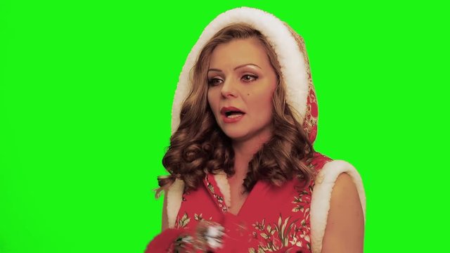 Pretty woman with curly hair wearing christmas costume and gloves and timbrel in her hands sings, forgets words makes gestures against chromakey.