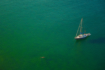 Luxury sailboat on green calm water aerial view