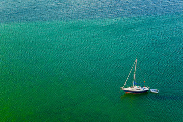 Luxury sailboat on green calm water aerial view
