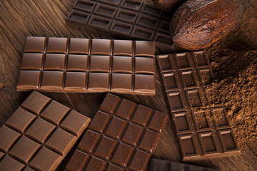 Chocolate bar, candy sweet, cacao beans and powder on wooden background