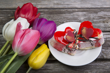 The dish with the cake and flowers tulips on wooden background