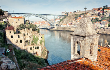 Fototapeta na wymiar Porto slums, view on Dom Luís I Bridge. Abandoned buildings church and river. Non-touristic wild place. Alternative route.
