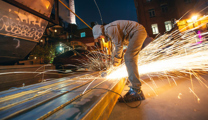 Professional worker cuts metal by electric saw. Fountain of sparks. Fire safety at construction...