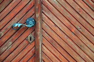 Diagonal texture of brown wooden door with old metal handle.