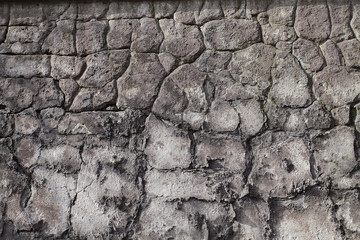 Background image of an old stone wall with cracks and remains of plaster