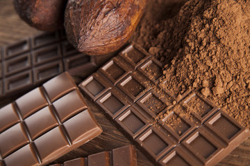 Chocolate bar, candy sweet, cacao beans and powder on wooden background