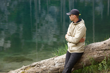 Young man on the shore of a mountain lake