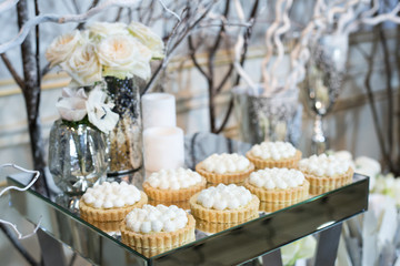 Cupcakes with white cream on the table decorated with white flowers and candles
