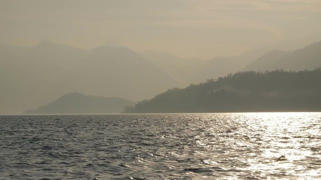 Evening rocky beach on a cloudy day. European Alps, Italy, Lake Como. Slow motion.