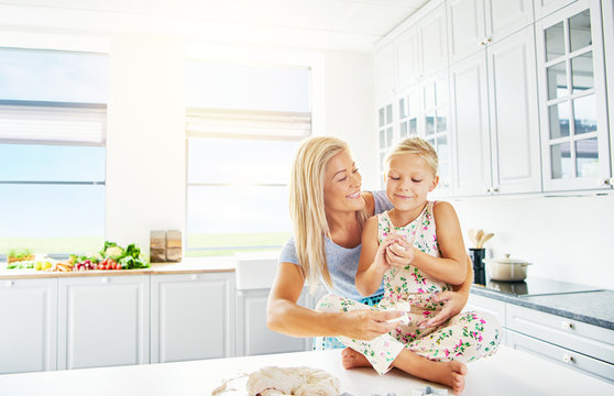 Girl Sitting On Kitchen Counter Beside Mother