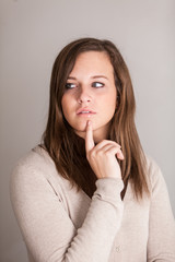 Fototapeta premium Thoughtful young brunette girl posing with finger under her chin