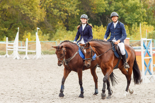 Young man and woman riding bay horses on equestrian competiton