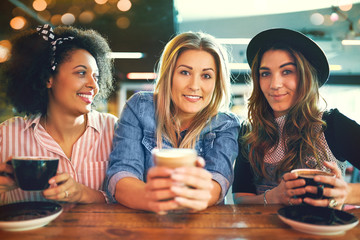 Three trendy young women enjoying coffee