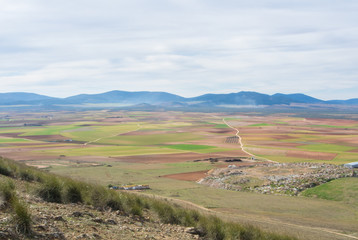 A view from a hill to fields, farms and mountains near Consuegra town at spring cloudy day.