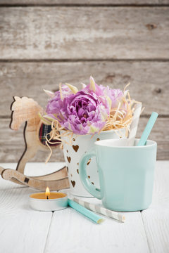 pink tulips, blue cup, straws, lit candle and rocking horse