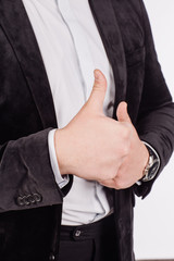 businessman looking at camera and showing his thumb up while standing against white background