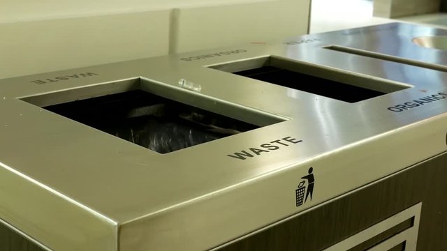 Woman throwing trash to the garbage can inside shopping mall