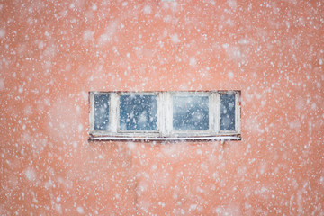 Snowfall over red background daytime window