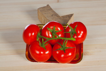 Five fresh red tomatoes with green stem in the tray , isolated on the background