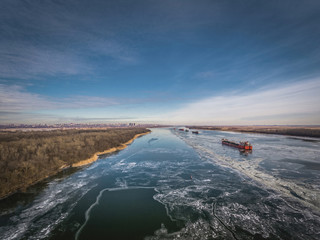 Cargo ship on the ice river in winter. Aerial view.