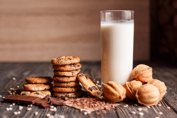 Chocolate chip cookies and filling and chocolate with milk on a dark wooden table