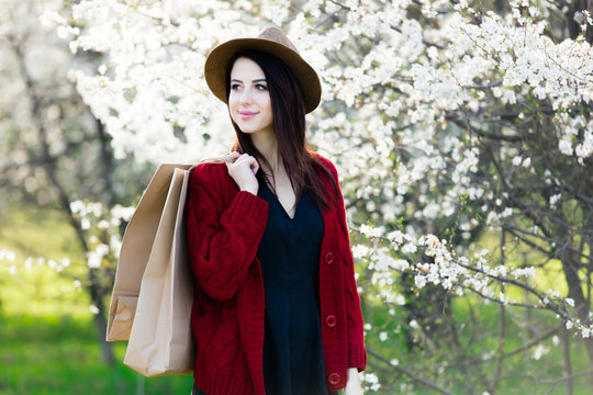 beautiful young woman with shopping bags standing in front of wonderful blooming trees background