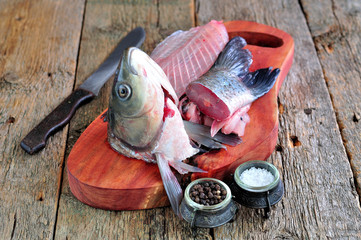 Fresh raw fish head and bones for soup, broth or sauce on a wooden background.