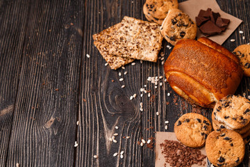 Homemade bun and a variety of cookies on a dark rustic wooden table with space for text.