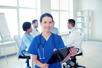 Fototapeta premium happy doctor with clipboard over group of medics