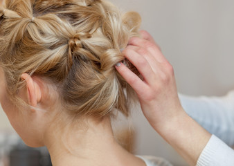 Naklejka premium Beautiful blonde girl with a beautiful, neat hairstyle, close-up in a beauty salon. Professional hair care and creating hairstyles.