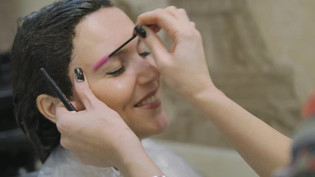 Young woman with hair in the paint, to eyebrow make-up sitting from the master image maker beauty salon ultra HD