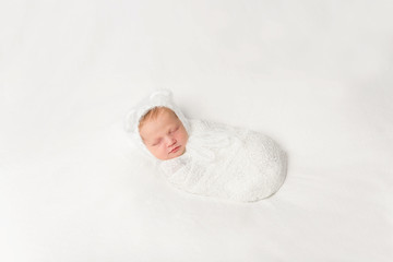 funny swaddled in white costume baby sleeping on blanket