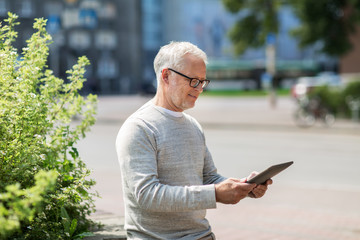 senior man with tablet pc on city street