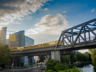 A yellow U-Bahn train is driving through houses of Kreuzberg, in Berlin.